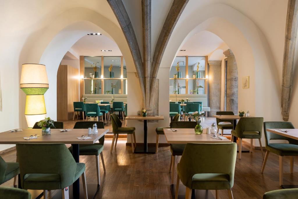 a restaurant with tables and chairs in a room at Altstadthotel Arch in Regensburg