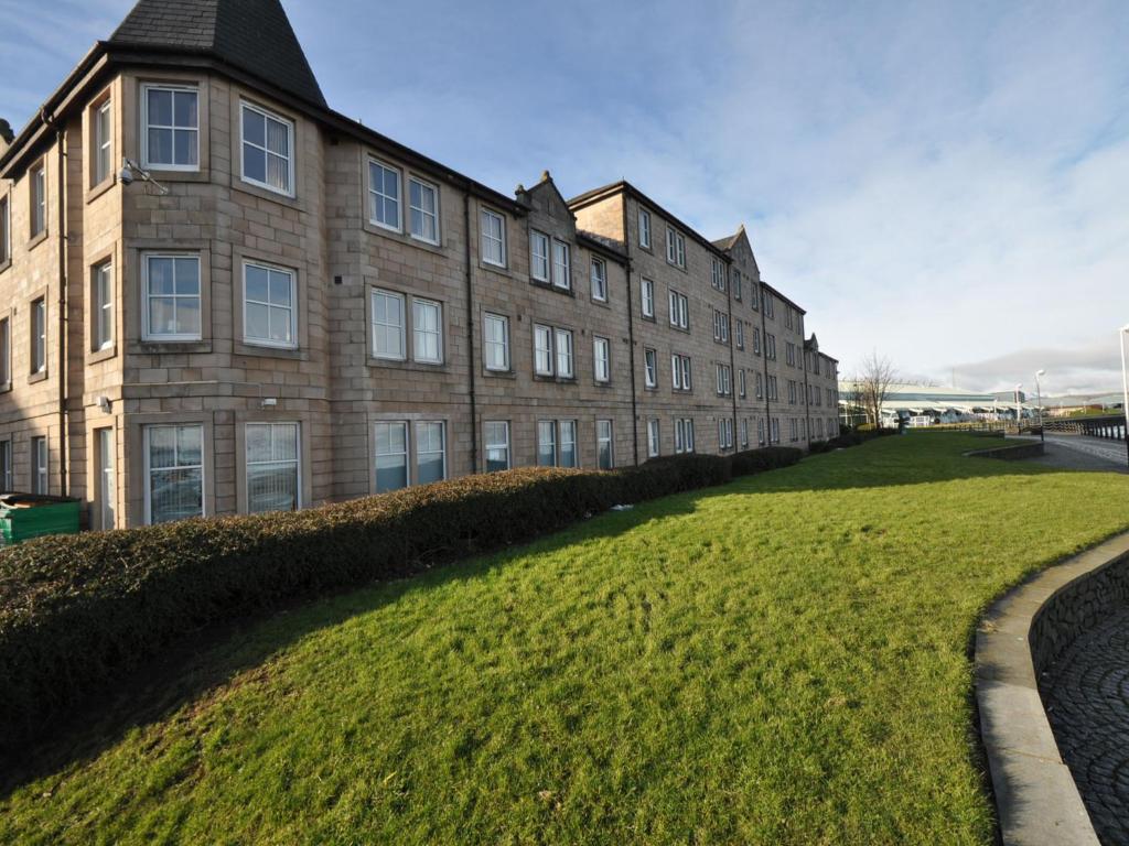 a large building with a grass field in front of it at The Waterfront in Greenock