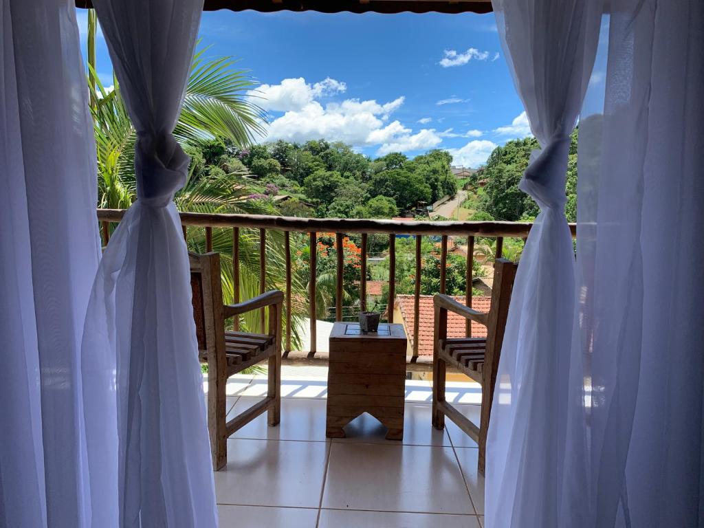 a balcony with white curtains and a table and chairs at Casa Boutique in Cunha