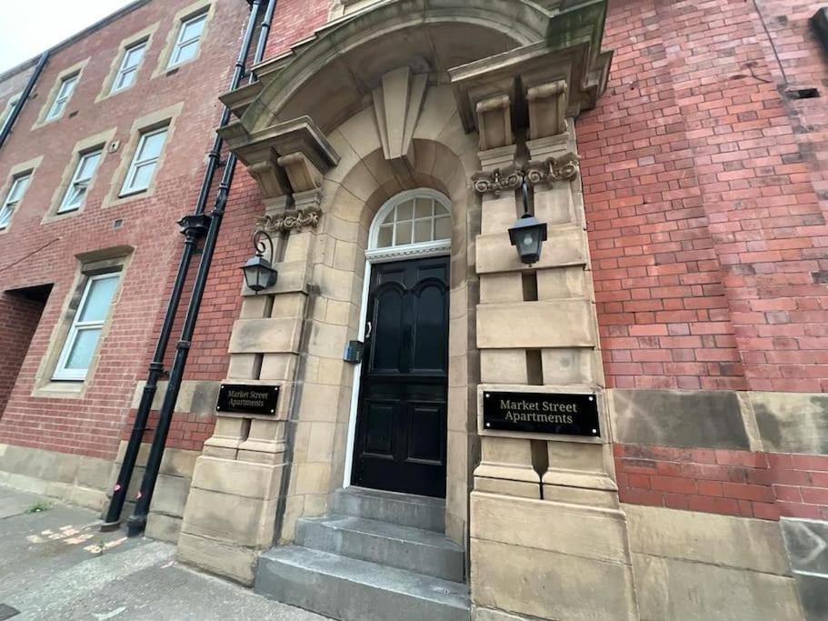 a building with a black door with a sign on it at Lovely One Bedroom Apartment in Rotherham