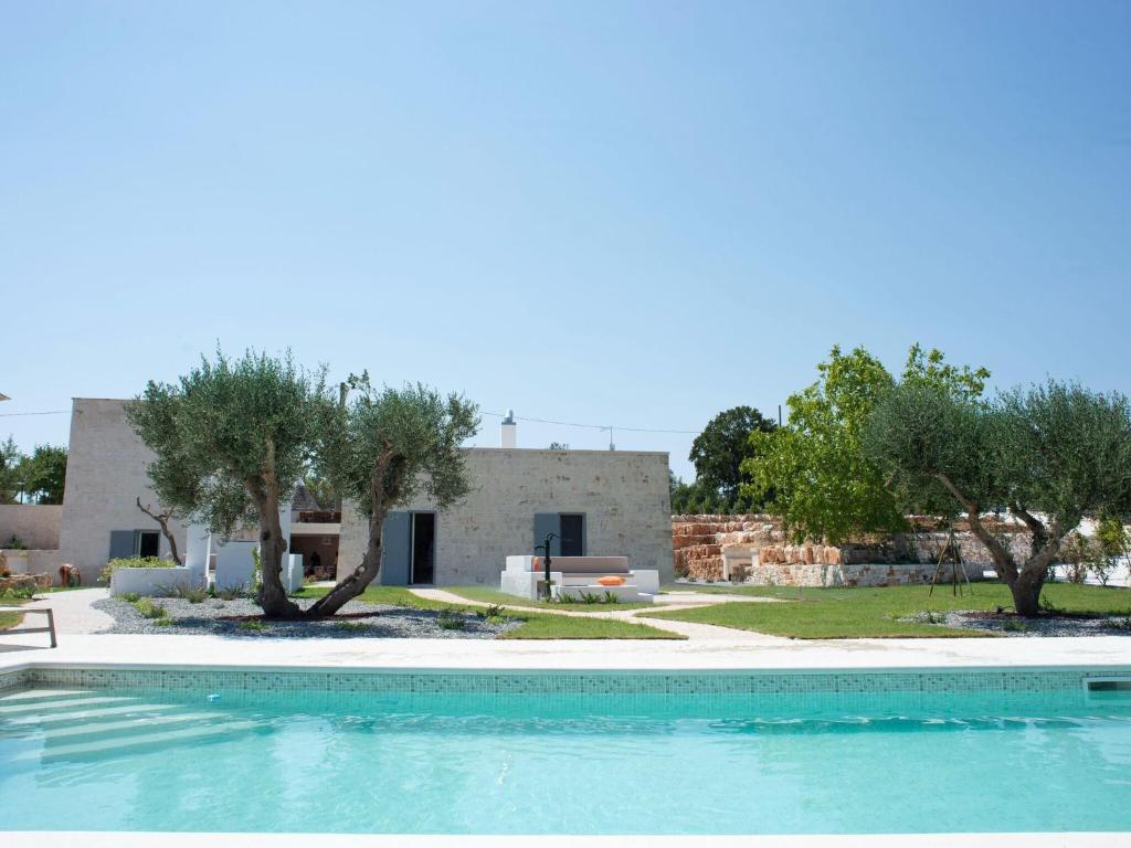 uma piscina em frente a uma casa com árvores em Charming holiday home with annex and pool near Cisternino em Cisternino