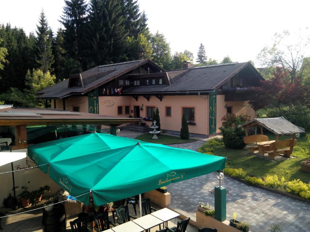 ein Haus mit einer Terrasse mit einem grünen Sonnenschirm in der Unterkunft Ski&Bike Nassfeld Apartments in Hermagor