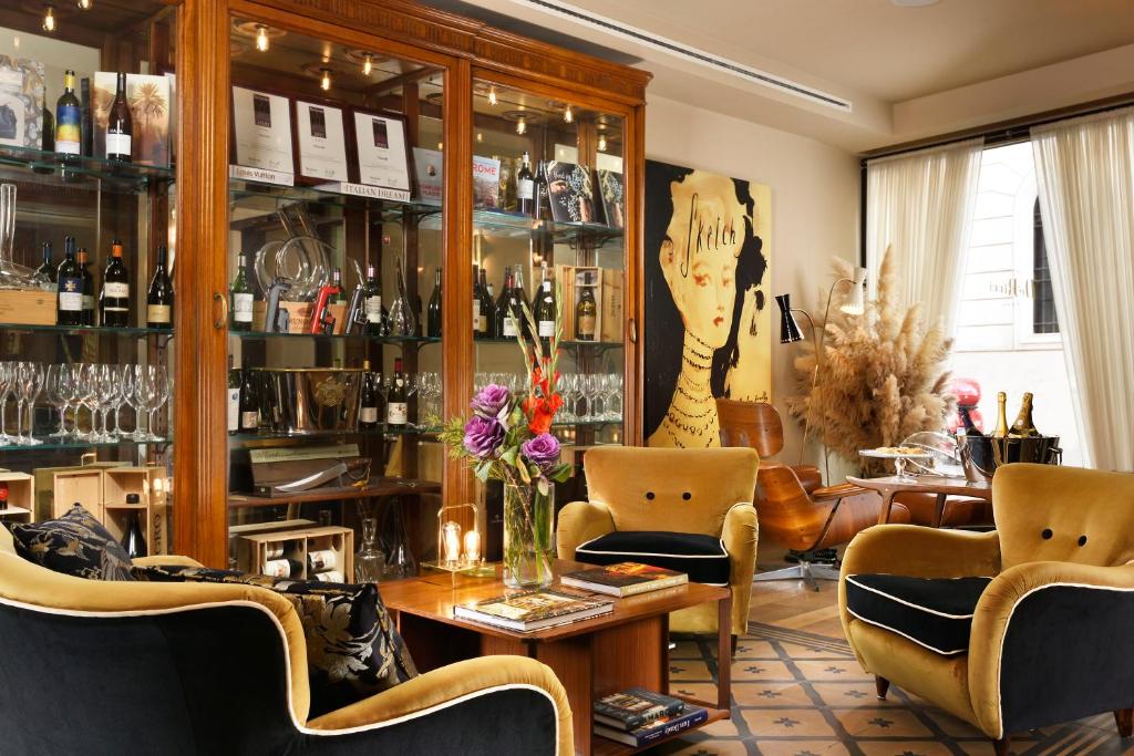 Hotel De' Ricci - Small Luxury Hotels of the World في روما: غرفة بها كراسي وطاولة عليها زهور