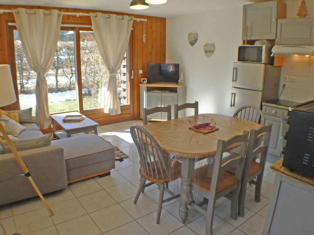 une cuisine et un salon avec une table et des chaises dans l'établissement T3 cosy avec terrasse, arrêt ski-bus, parking privé, animaux admis, proche centre-village - FR-1-629-96, à Samoëns