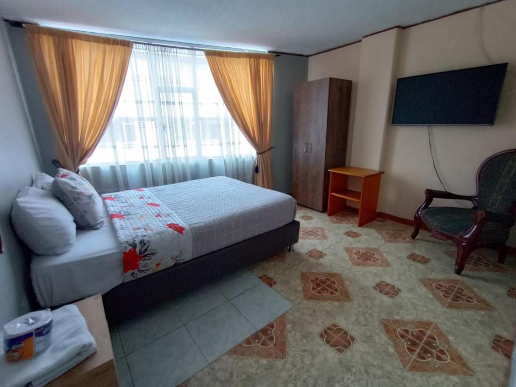 a bedroom with a bed and a chair and a window at HOTEL DINO in Pasto
