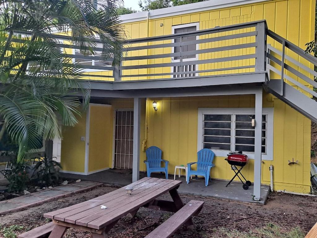 a yellow house with two blue chairs and a picnic table at CRUCIAN SECLUSION in Christiansted