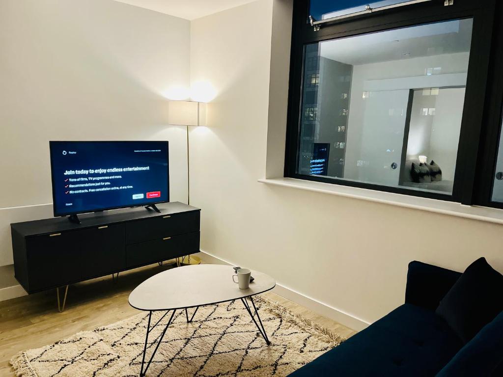 a living room with a tv and a coffee table at Brand new modern 1 bed apartment near Old Trafford Stadium in Manchester