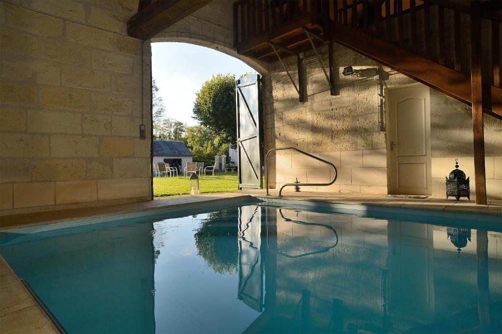a swimming pool in a stone building with a water fountain at La Folie Saint Julien in Saint-Julien-de-Chédon