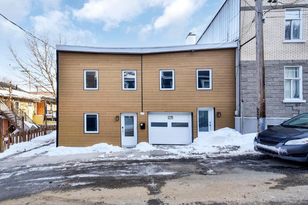 un edificio con dos puertas y un coche aparcado delante en 2-storey house with garage and interior terrace, en Quebec