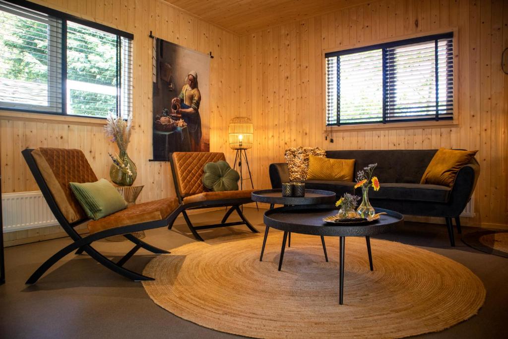 a living room with a couch and chairs and a table at Vakantiehuisje Jipué met sauna en bubbelbad. in Bruchterveld
