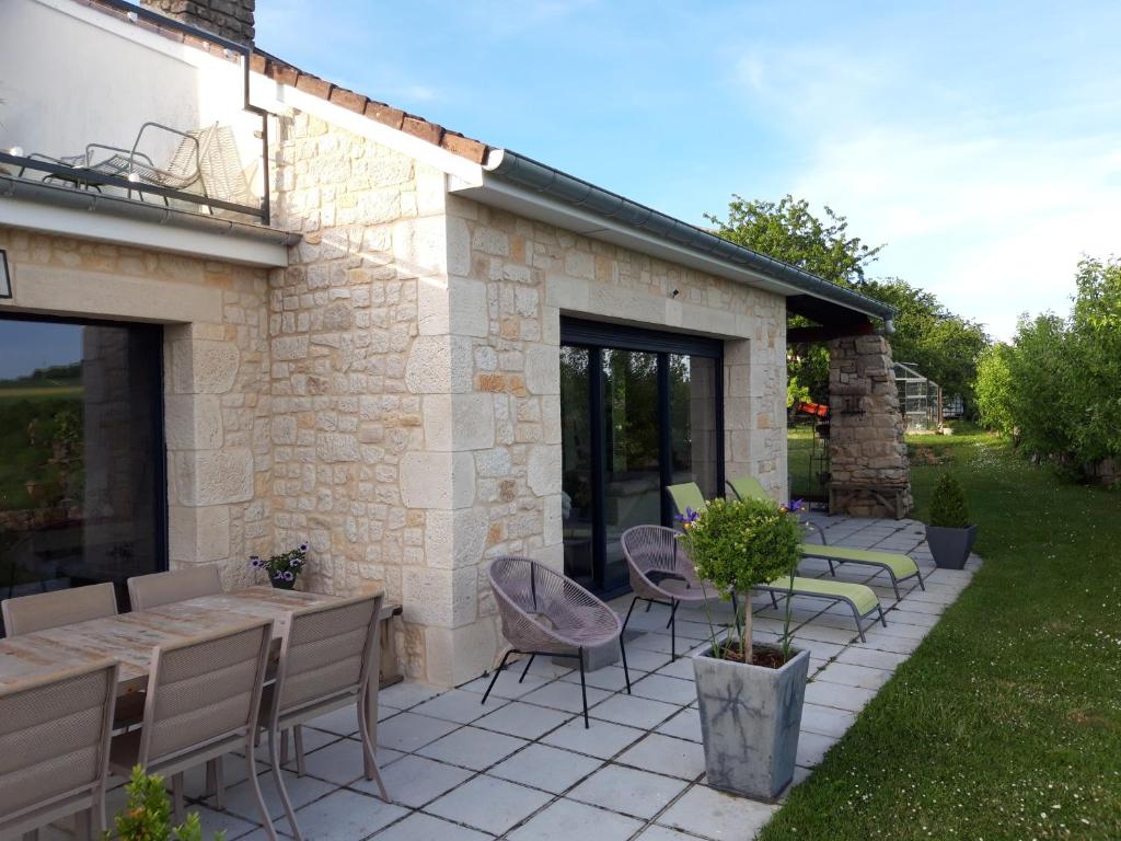 eine Terrasse mit einem Tisch und Stühlen sowie ein Gebäude in der Unterkunft B&B CHEZ FOUCHS - Chambre d'hôtes in Dun-sur-Meuse