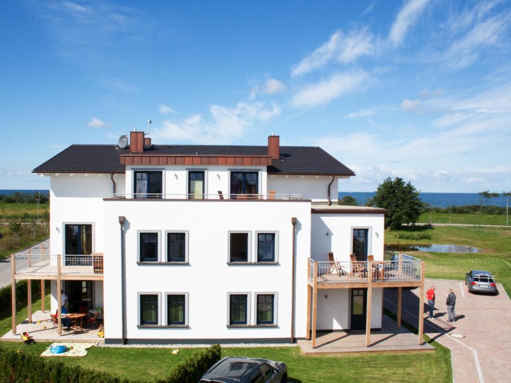 ベルガーエンデ・レートヴィッシュにあるFerienwohnungen Strandvilla Börgerendeのバルコニーと海が備わる広い白い家です。