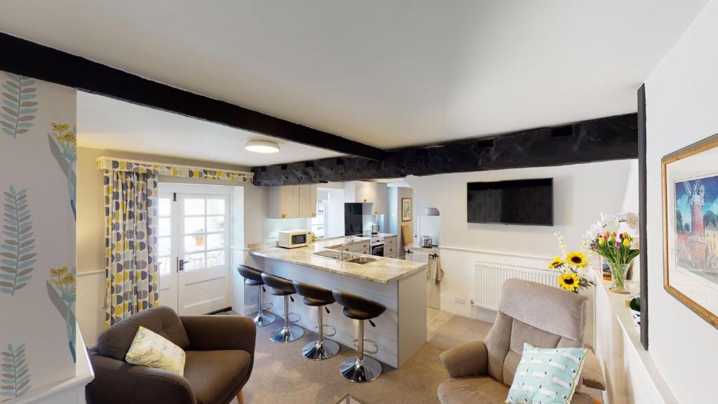 eine Küche und ein Wohnzimmer mit einer Bar und Stühlen in der Unterkunft Cider Cottage in Sidmouth