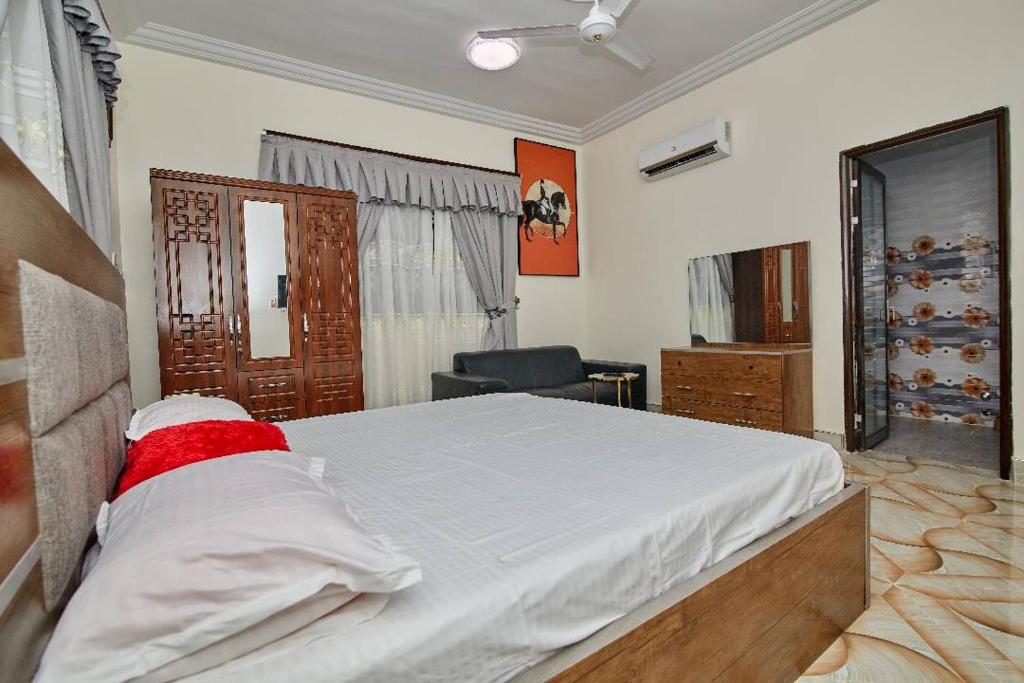 a bedroom with a large bed and a chair at POMAA VILLA in Kumasi