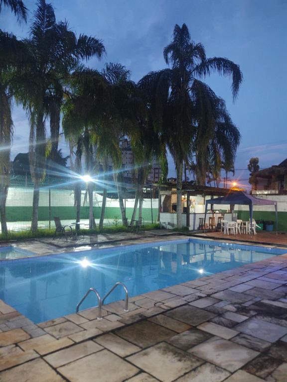 a swimming pool with palm trees in the background at Pousada Praia Grande - Rua Ernesto Vergara ,511 in Praia Grande