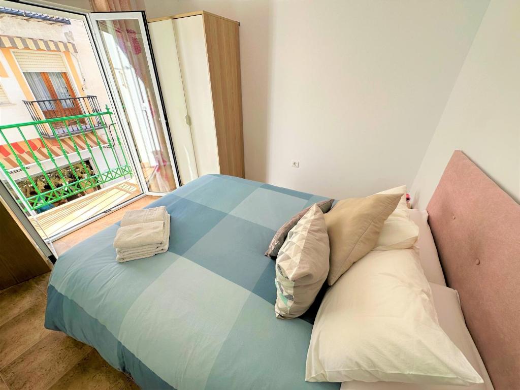 1 dormitorio con cama con almohadas y ventana en Casa Jazmi­n, en Nerja