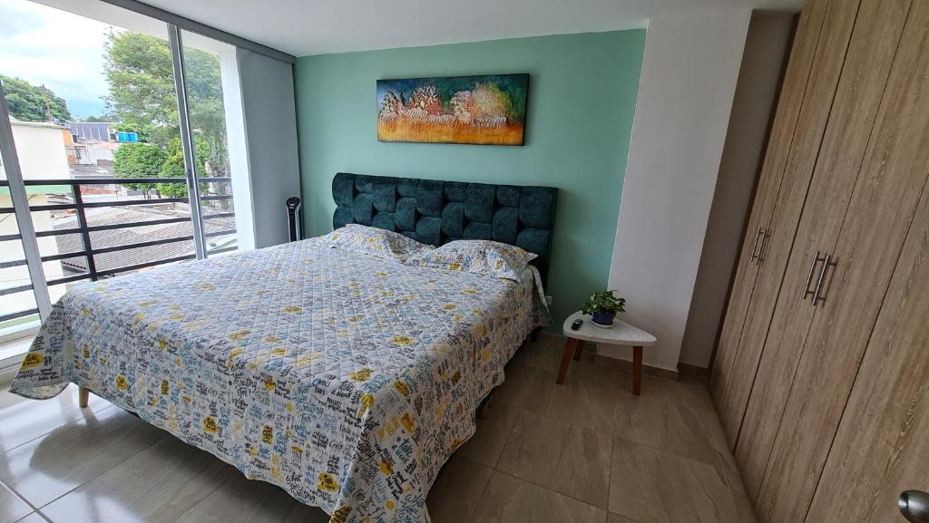 1 dormitorio con cama con colcha azul y ventana en Hermoso Apartamento Entero - Parqueadero - Pino, en Ibagué