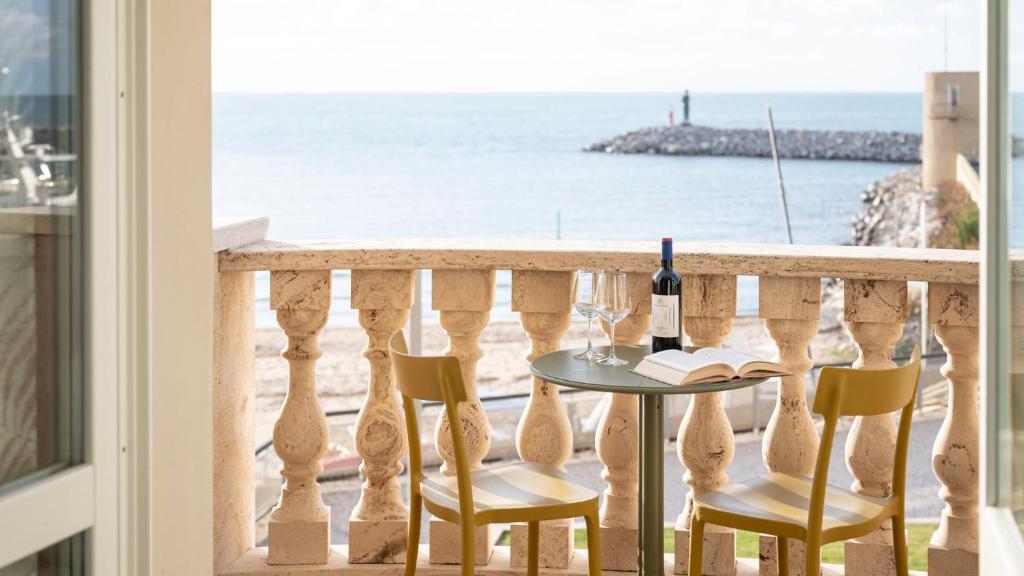 un tavolo con sedie e una bottiglia di vino su un balcone con vista sull'oceano di Suite vista mare a San Vincenzo