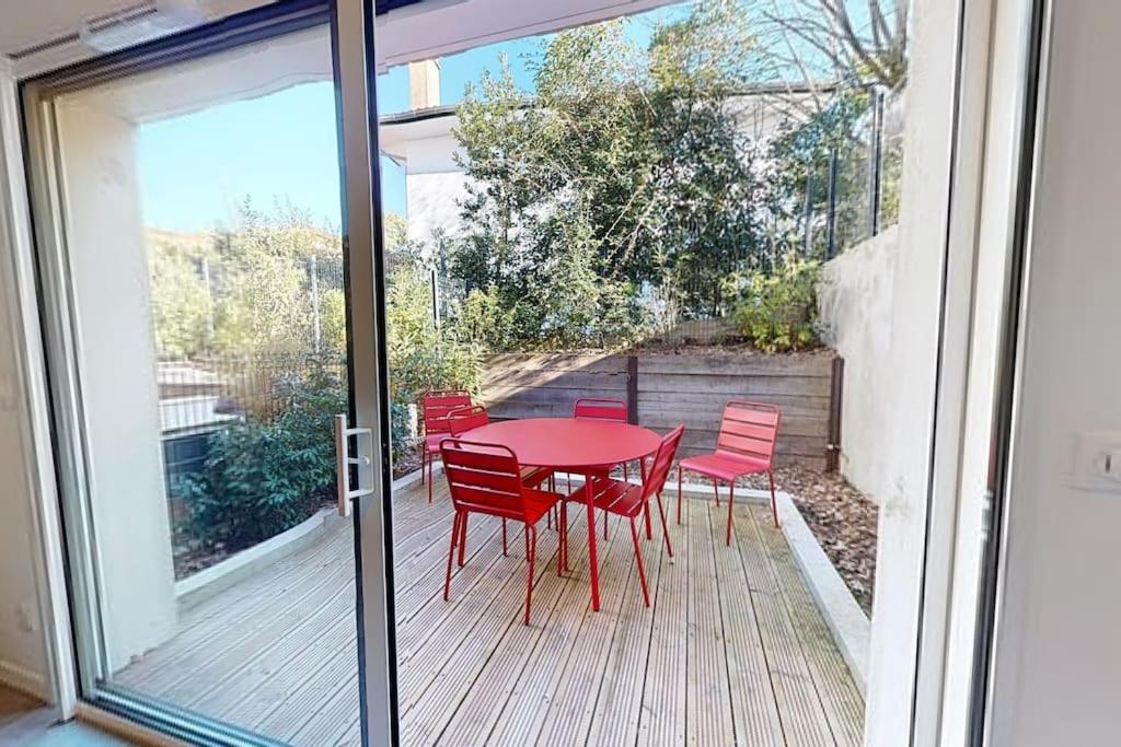 a patio with a red table and chairs on a deck at TERRASSES SAINT GEORGES - Un emplacement exceptionnel au centre-ville et au calme à quelques pas du lac marin in Soorts-Hossegor