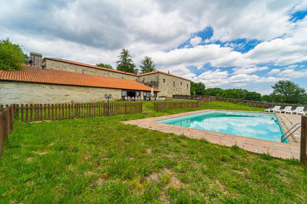 a swimming pool in a yard next to a building at Casa Rural Pazo San Damian in Amoeiro