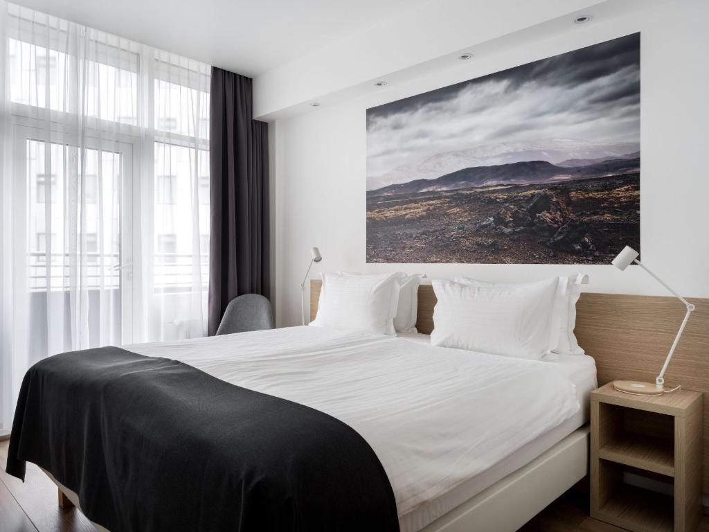 ein Schlafzimmer mit einem weißen Bett und einem Gemälde an der Wand in der Unterkunft Storm Hotel by Keahotels in Reykjavík