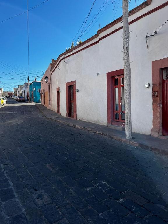 an empty street next to a white building with red doors at Departamento en Centro de Querétaro in Querétaro
