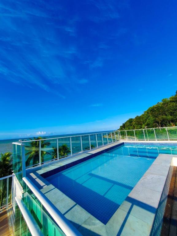 a swimming pool on top of a building with the ocean in the background at Home service na praia de Cabo Branco in João Pessoa