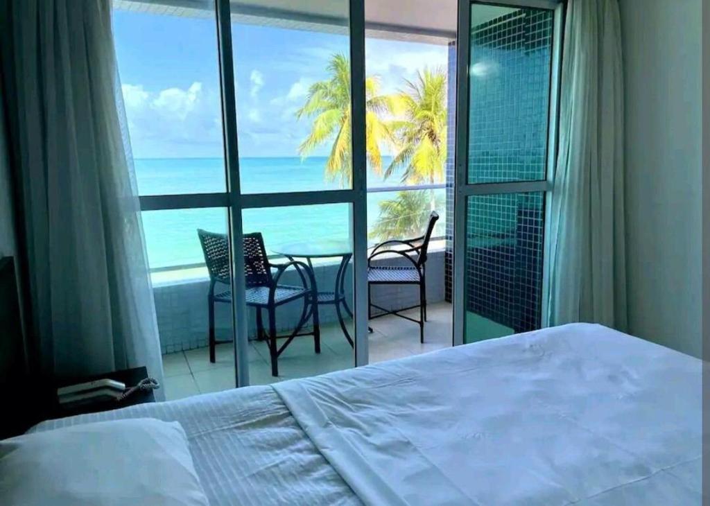 a bedroom with a bed and a view of the ocean at Home service na praia de Cabo Branco in João Pessoa