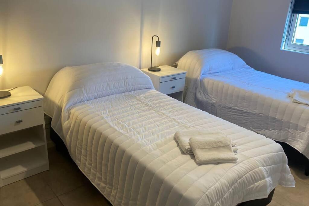 1 dormitorio con 2 camas, 2 mesas y una lámpara en Apto. Residencial Cardinales en Córdoba