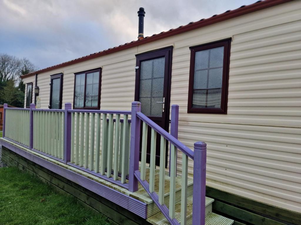 Casa móvil con porche púrpura y ventanas en Castlewigg holiday park Whithorn 2 bed caravan, en Newton Stewart