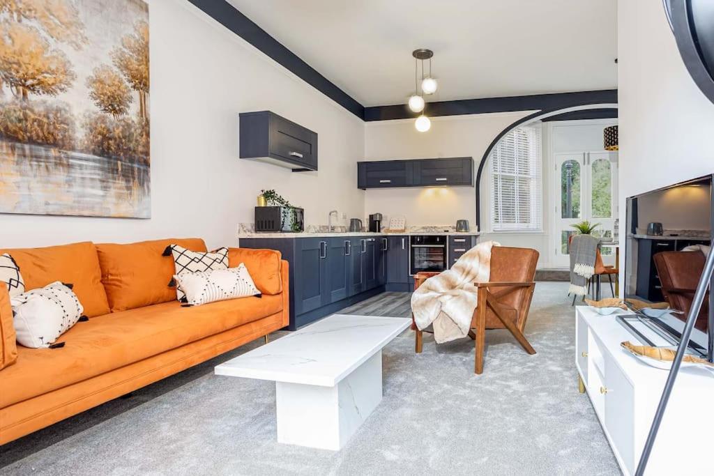 een woonkamer met een oranje bank en een keuken bij Coppergate Mews Grimsby No.2 - 2 bed, 2 bath, ground floor apartment in Grimsby