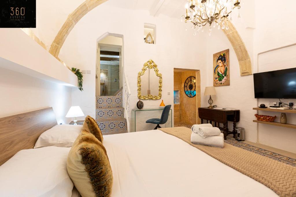 a bedroom with a large white bed and a tv at 1BR Charming townhouse in capital city with WIFI by 360 Estates in Valletta