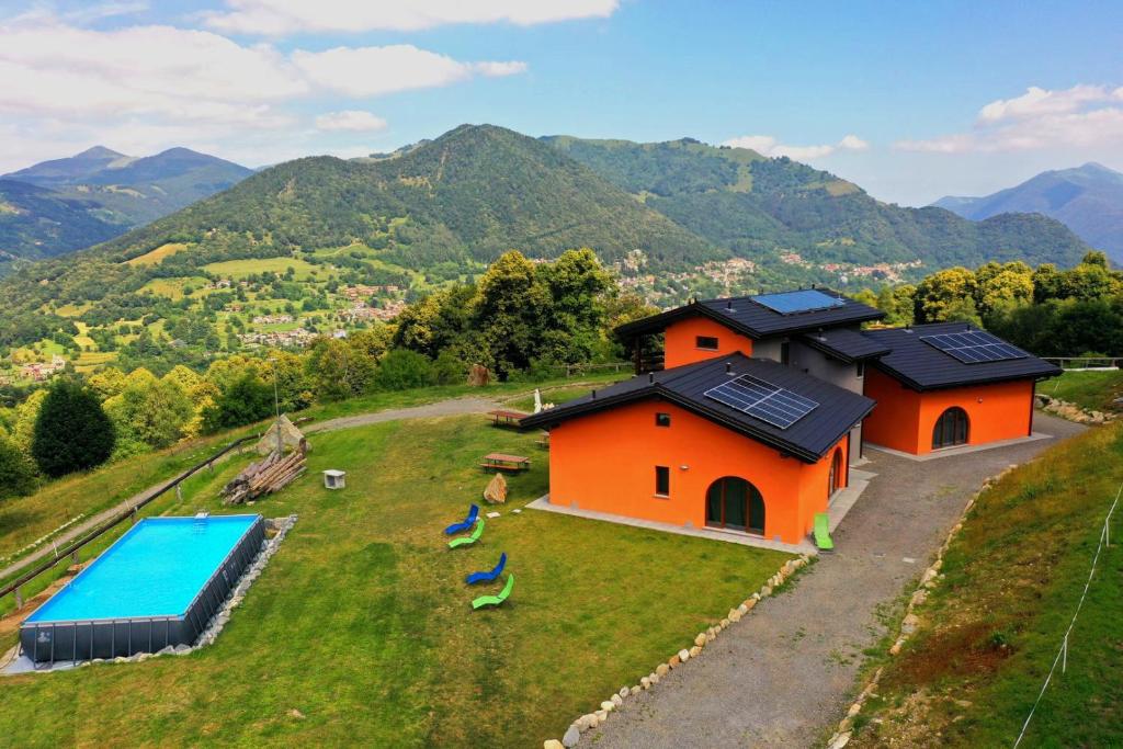 Agriturismo Baita Bavè في San Fedele Superiore: منزل برتقالي على تلة مع حمام سباحة