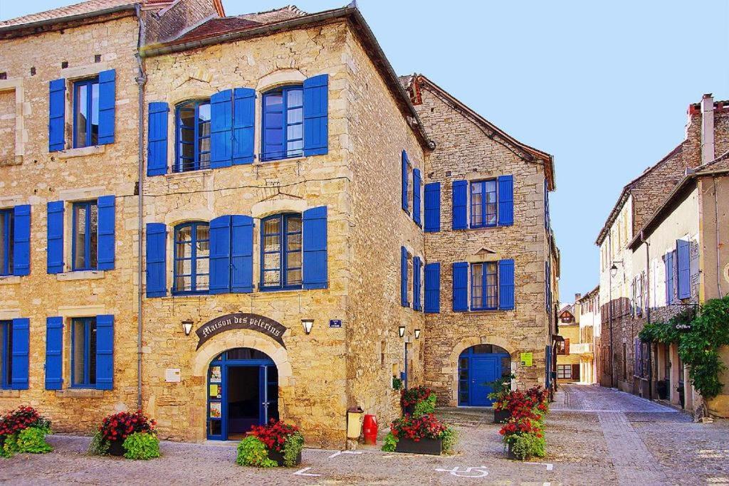 un antiguo edificio de ladrillo con persianas azules en una calle en La Maison des Pélerins Villeneuve, en Villeneuve-dʼAveyron