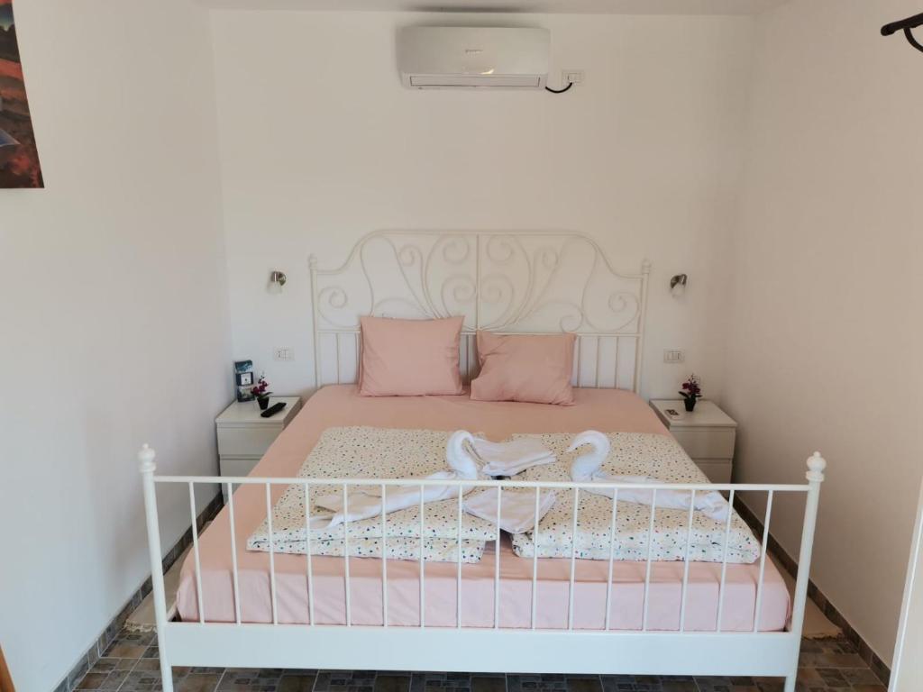 un letto bianco con cuscini rosa e una culla di Pensiunea Blue House a Vadu