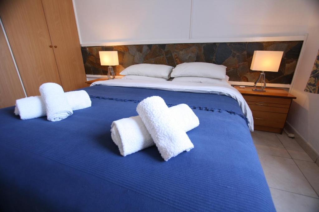 a blue bed with two white towels on it at Pissouri Beach Apartments in Pissouri