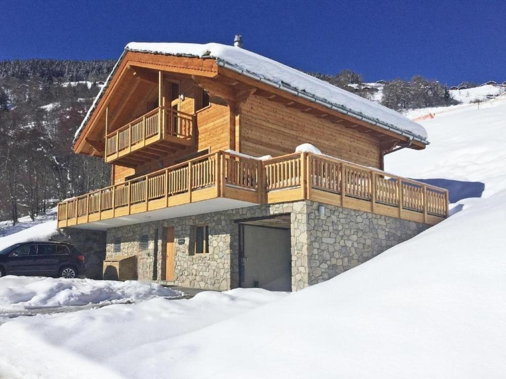 a log cabin with a balcony in the snow at Chalet des Etoiles Les Masses in Hérémence