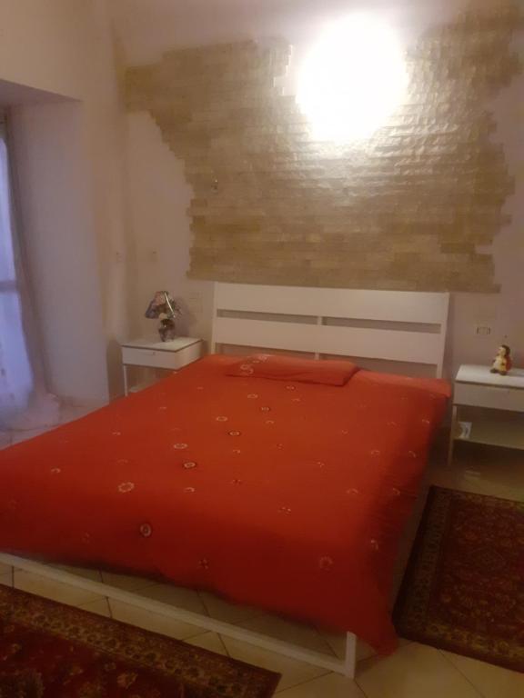 1 dormitorio con 1 cama roja y 2 mesas en Oasi, en Prevalle