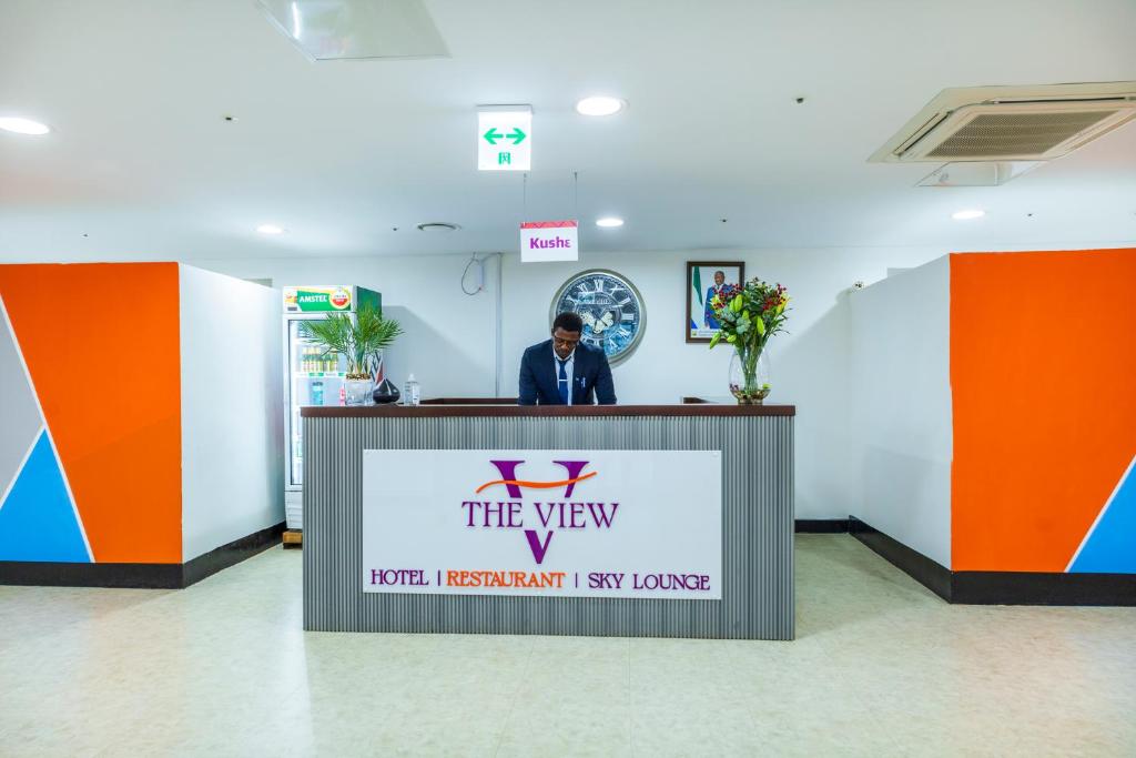 a man standing at a reception desk in a lobby at The View Hotel Restaurant & Sky Lounge in Freetown