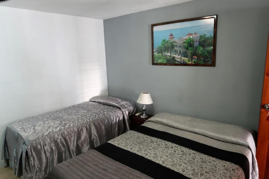 a bedroom with two beds and a picture on the wall at Casa Amigos de Barcelo Appartement 1 in Cienfuegos