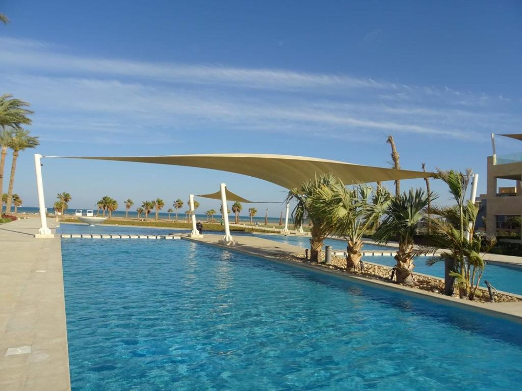 a swimming pool with a canopy over it with palm trees at Mangroovy Ritzy, Cerulean appartement by the pool in Hurghada