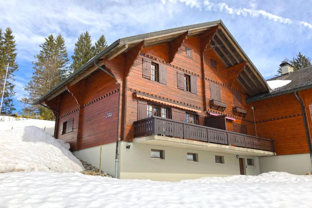 a large wooden building with a balcony in the snow at Résidence « la Forêt » in Les Mosses