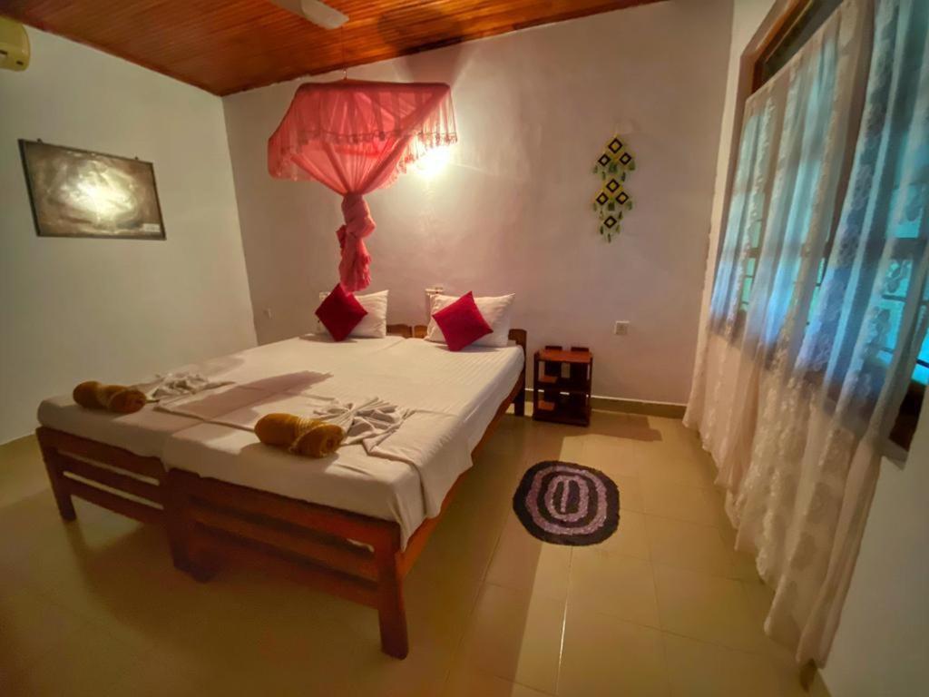 a bedroom with a bed with a red lamp on it at Globetrotter Tourist Inn in Sigiriya