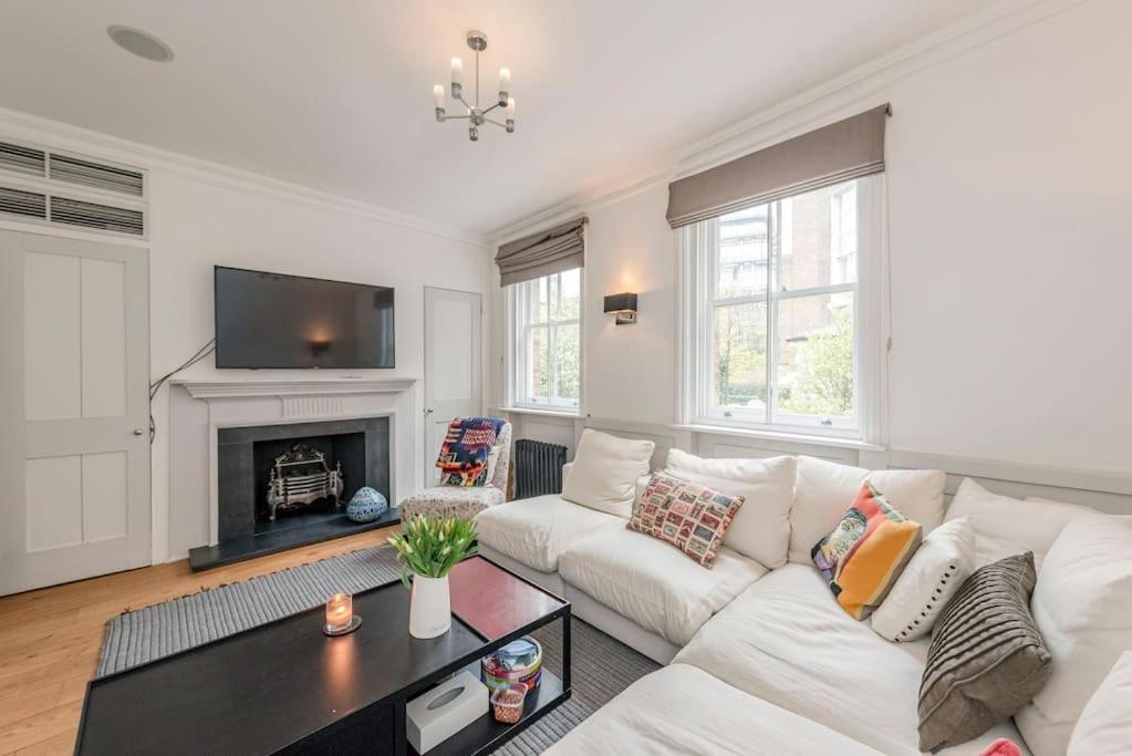 a living room with a white couch and a fireplace at Stunning 3 Bed Townhouse in the heart of Mayfair in London