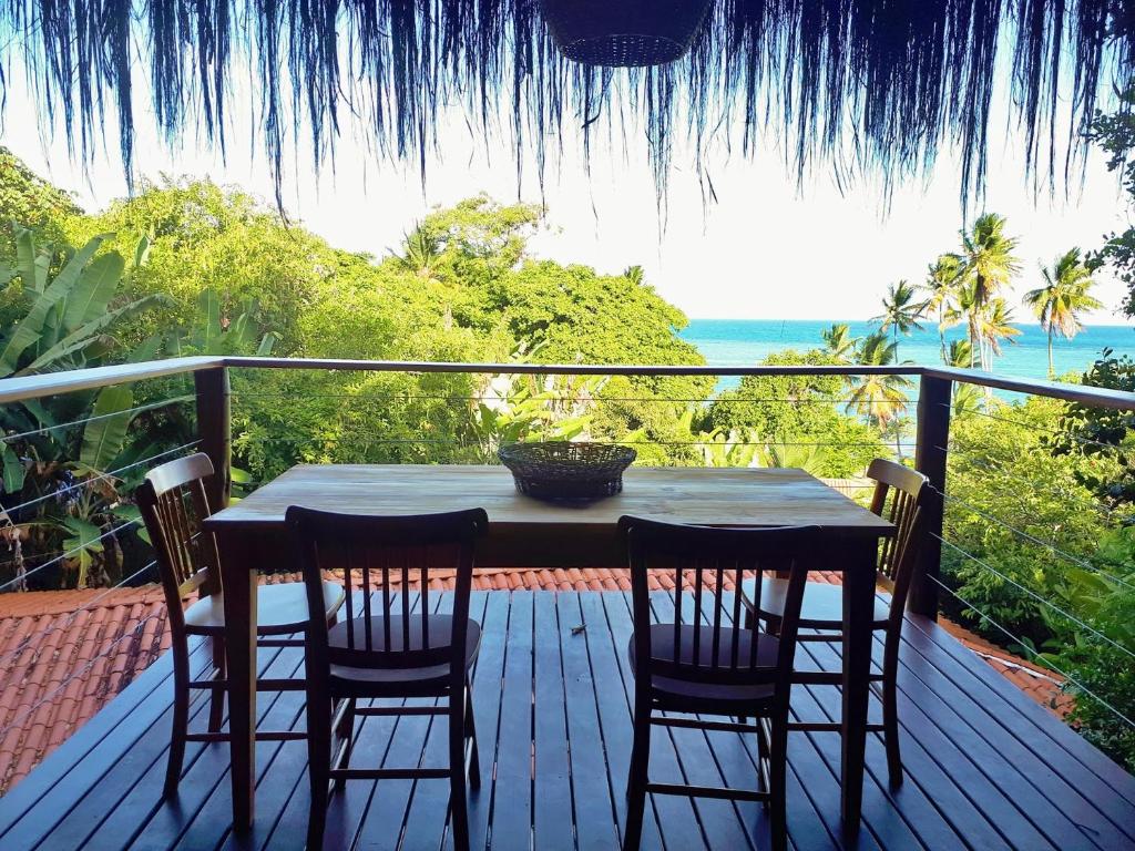 a table and chairs on a deck with a view of the ocean at Saudade da Bahia in Moreré