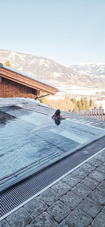 a person is swimming in a swimming pool at Bergdorf Hotel Zaglgut in Kaprun