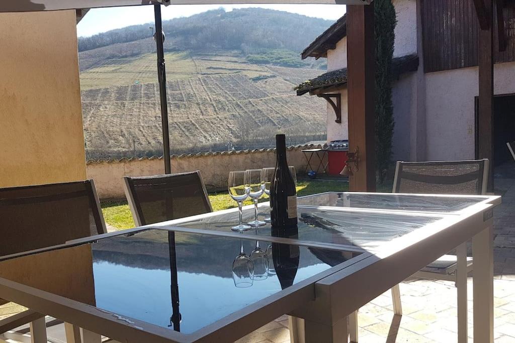 una mesa de cristal con 2 copas de vino y vistas en Charmante maison au calme pour 6 personnes, en Quincié-en-Beaujolais