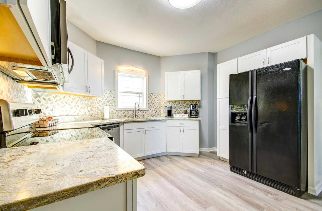 a kitchen with white cabinets and a black refrigerator at Warrensburg Home, Close to Downtown! in Warrensburg