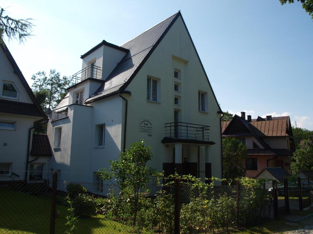 a white house with a gambrel roof at Pokoje Gościnne Żak in Zakopane