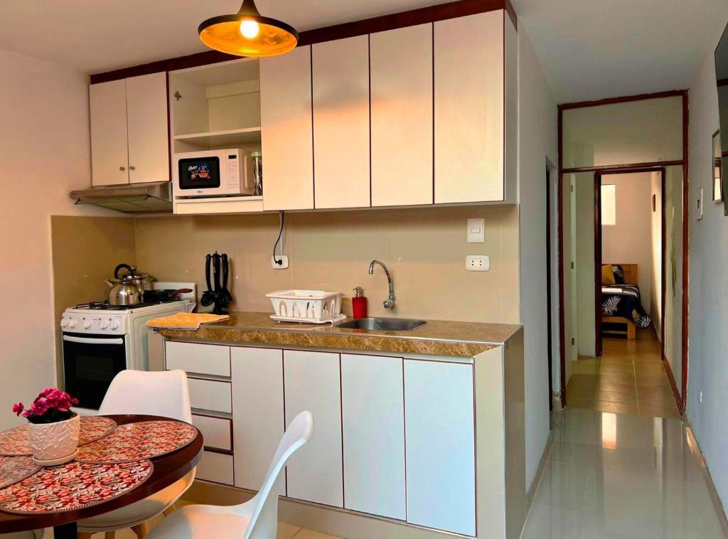 cocina con armarios blancos, mesa y comedor en Lindo dpto con vista al jardin, internet y cable, en Lima